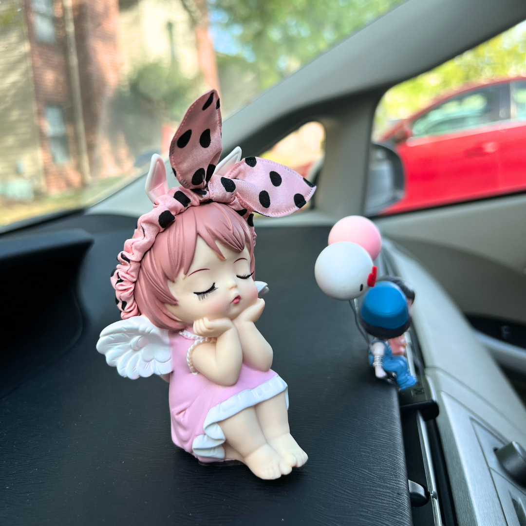 Adorable angel figurine with bunny ears and pink dress, sitting on a car dashboard, adding a whimsical touch to the interior.