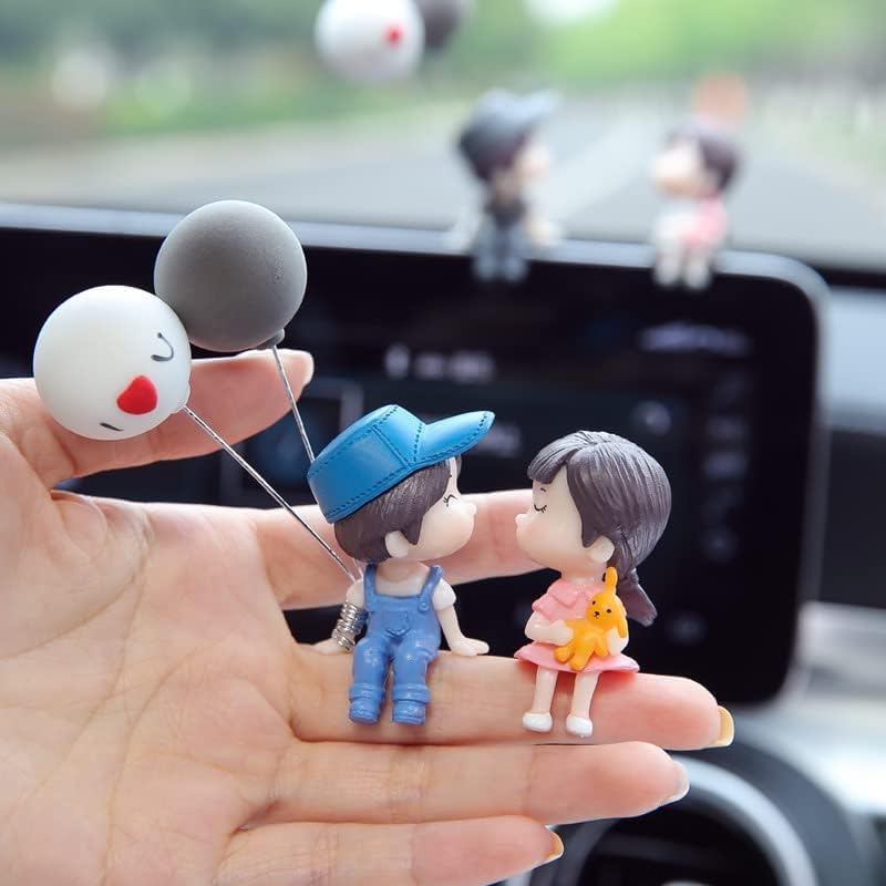 Hand holding cute couple figurines with balloons, perfect for car decoration.